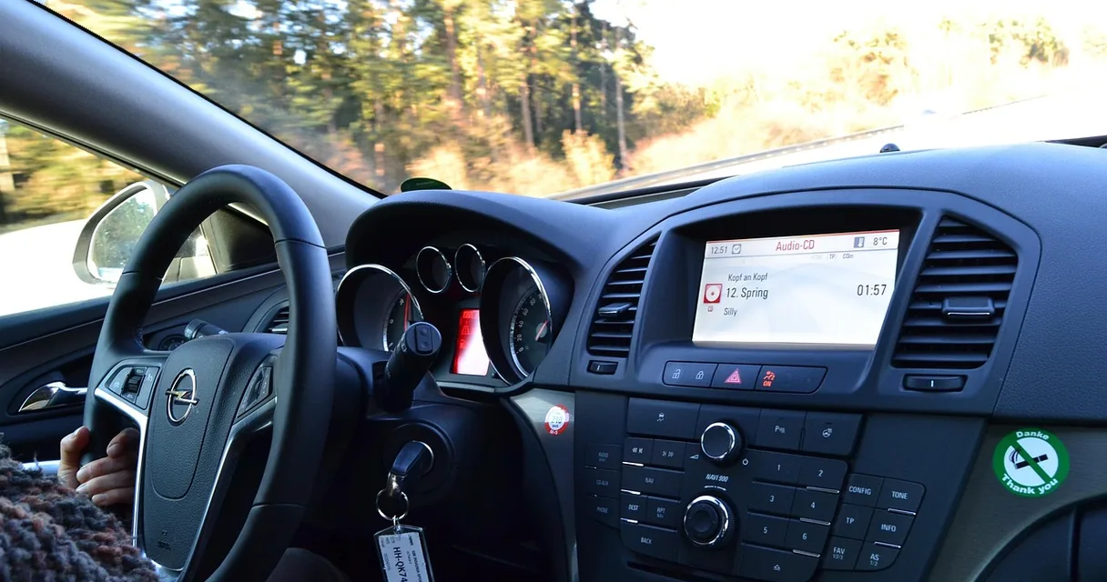 Volante e painel de um carro vistos do banco do motorista em uma estrada